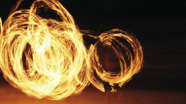 Feuerkünstler schwingen brennende Fackeln in der Dunkelheit.