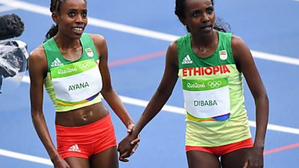 Die äthiopischen Läuferinnen Ayana und Dibaba halten Händchen auf der Laufbahn.