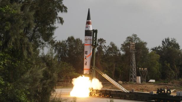 Eine Rakete startet von einer mobilen Abschussrampe in einer bewaldeten Umgebung.