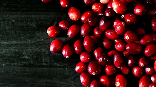 Eine Ansammlung von roten Cranberries auf einer dunklen Holzoberfläche.