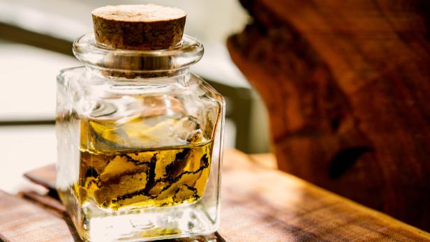 Eine Glasflasche mit Trüffelöl steht auf einem Holzbrett.