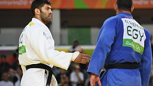 Zwei Judoka stehen sich gegenüber, einer im weißen, der andere im blauen Anzug.