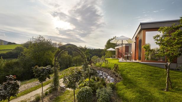 Ein Garten führt zu einem modernen Haus mit Terrasse und Blick auf die Landschaft.