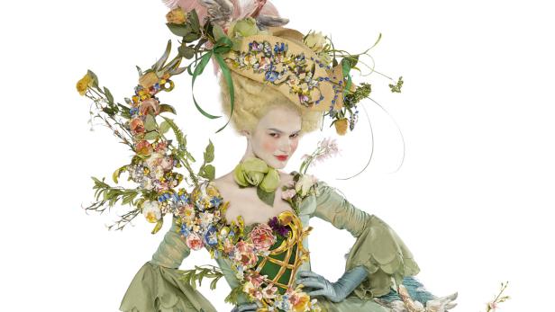 Eine Frau in einem historischen Kostüm mit Blumen und einem aufwendigen Hut.