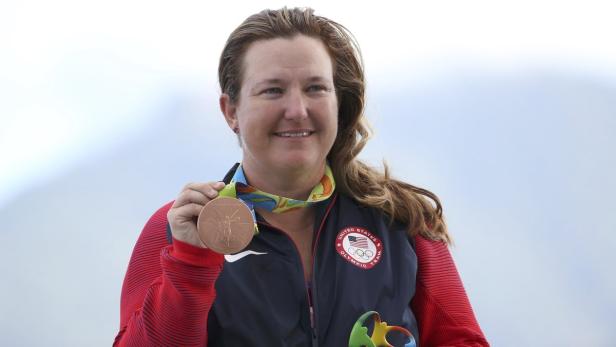 Eine Frau mit einer Bronzemedaille der Olympischen Spiele um den Hals lächelt.