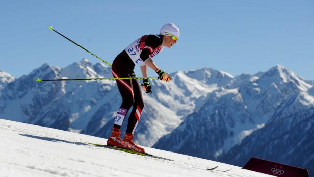 Eine Langläuferin fährt vor einer Bergkulisse Ski.