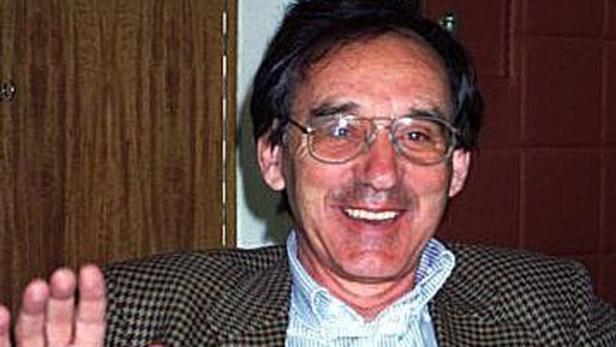 Ein lächelnder Mann mit Brille und kariertem Sakko.