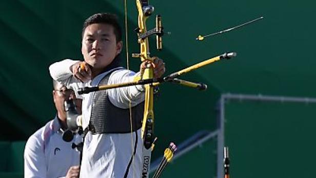 Ein Bogenschütze zielt mit Pfeil und Bogen auf eine Zielscheibe.