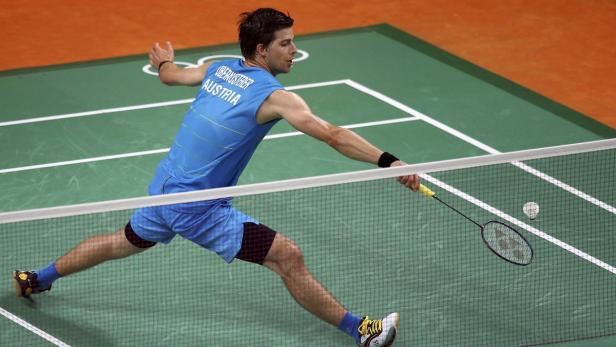 Ein Badmintonspieler aus Österreich schlägt einen Ball über das Netz.
