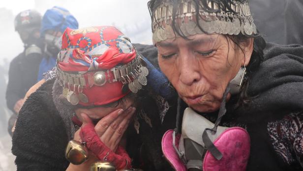 Am Sonntag versammelten sich tausende Mapuche in der chilenischen Hauptstadt Santiago, um gegen das Vorgehen Piñeras zu demonstrieren. Diese beiden Frauen versuchen, dem Tränengas der Polizei zu entkommen.