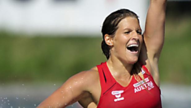 Eine österreichische Kanutin jubelt mit erhobenem Arm nach einem Rennen.