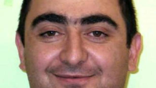 Porträt eines lächelnden Mannes vor einem hellgrünen Hintergrund.