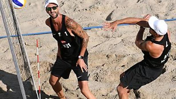 Zwei Männer spielen Beachvolleyball im Sand.