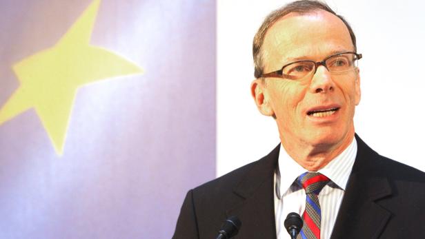 Ein Mann mit Brille spricht vor einem Hintergrund mit einem gelben Stern.