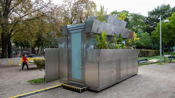 Eine moderne, öffentliche Toilette mit Pflanzen auf dem Dach in einem Park.
