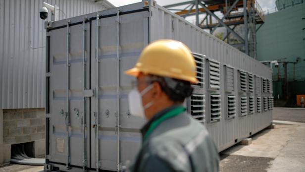 A worker is seen next to a container, where a Bitcoin mining facility is installed, at the Berlin geothermal plant of La Geo electrical company, in Alegria