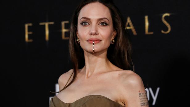 Angelina Jolie bei der Premiere von „Eternals“ mit einem goldenen Schmuckstück an der Lippe.
