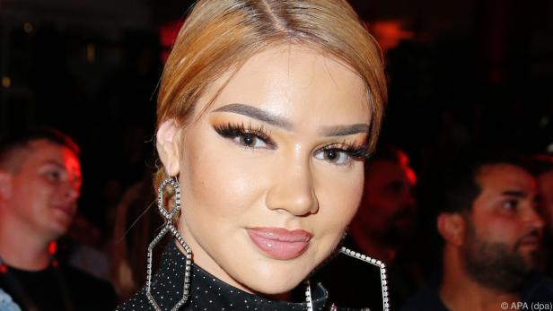 Shirin David mit opulenten Strassohrringen und einer blonden Dutt-Frisur bei einem öffentlichen Auftritt.