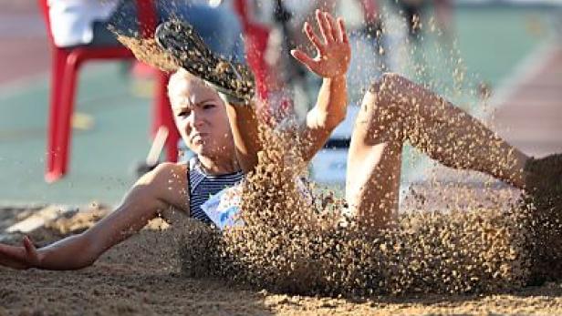 Eine Weitspringerin landet in der Sandgrube.