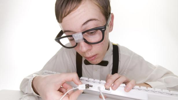 Teenage computer geek, hooking up computer, white indoor studio