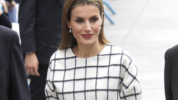 Königin Letizia mit einer roten Clutch und einem karierten Oberteil.