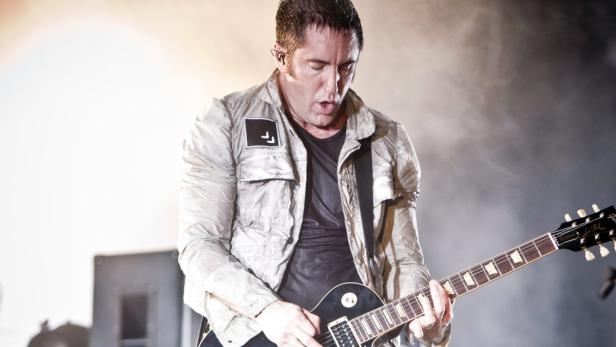 Trent Reznor von Nine Inch Nails spielt Gitarre auf der Bühne.