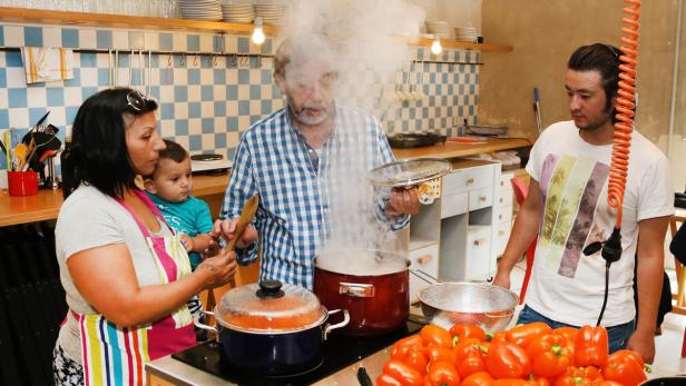 Mert Simsek mit Baby Munever und Muttahar helfen Koch Manfed Buchinger bei der Zubereitung