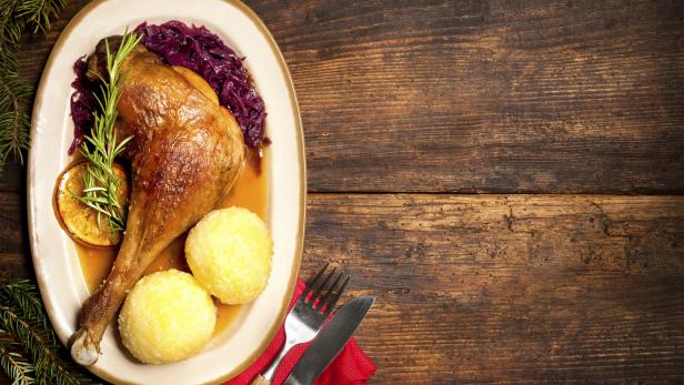 Ein Teller mit knuspriger Gänsekeule, Rotkohl und Kartoffelknödeln.