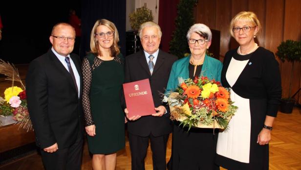 Eine Gruppe von fünf Personen posiert mit einer Urkunde und einem Blumenstrauß.