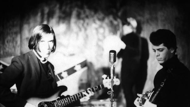 Ein Schwarzweißfoto von John Cale und Lou Reed bei einem Auftritt von The Velvet Underground.