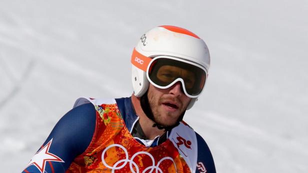 Ein Skirennläufer mit Helm und Skibrille vor einer verschneiten Piste.
