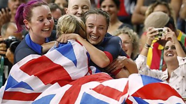 Britische Athletinnen umarmen sich freudestrahlend mit der Union Flag im Publikum.