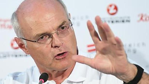 Ein Mann mit Brille gestikuliert vor einem Mikrofon.