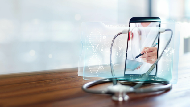 Ein Smartphone zeigt einen Arzt im Videoanruf, daneben liegt ein Stethoskop.