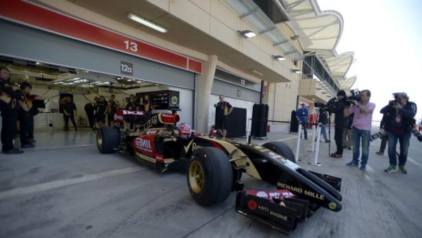 Ein Formel-1-Rennwagen steht vor einer Garage, umringt von Teammitgliedern und Fotografen.