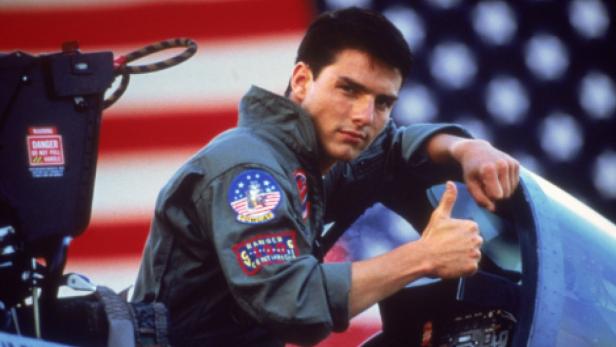 Tom Cruise als Pete „Maverick“ Mitchell in „Top Gun“ vor einer US-Flagge.