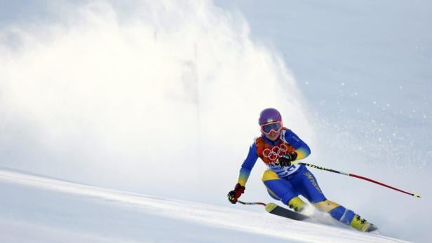 Eine Skifahrerin in blau-gelbem Anzug fährt einen Hang hinunter.
