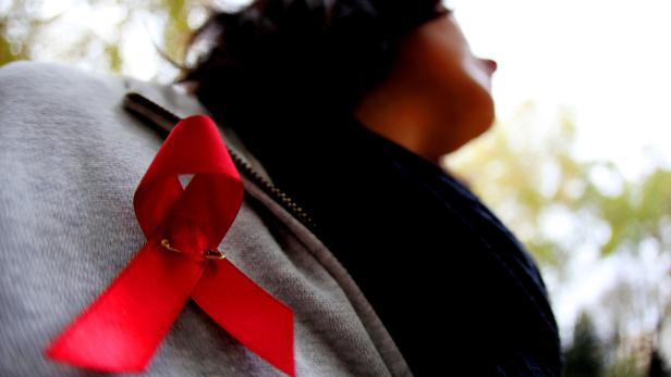 Eine rote Schleife, das Symbol für Solidarität mit HIV-Infizierten, ist an einer Jacke befestigt.