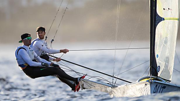 Zwei Segler steuern ein Segelboot auf dem Wasser.