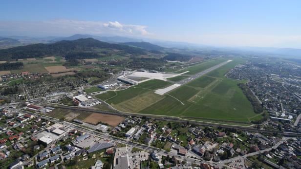 Luftaufnahme des Flughafens Klagenfurt mit Blick auf die Stadt und die umliegende Landschaft.