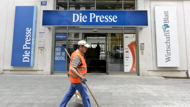 Ein Mann kehrt vor dem Gebäude der Zeitung „Die Presse“ die Straße.