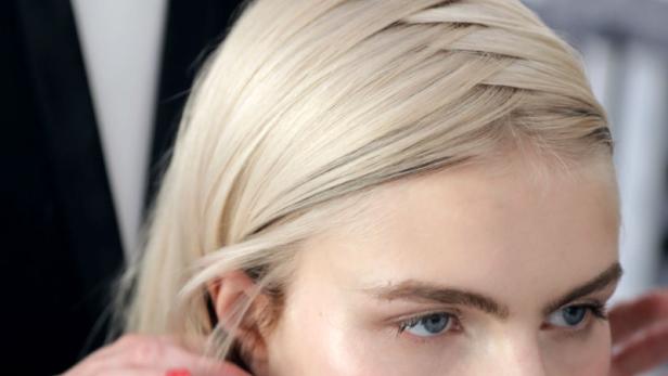 Eine Frau mit blonden Haaren wird von einem Stylisten frisiert.