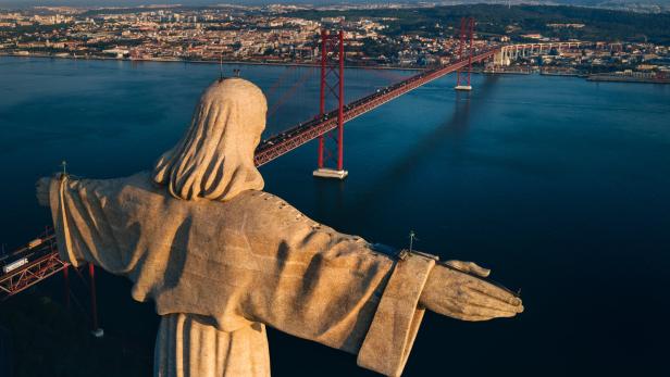 Die Cristo Rei Statue mit der Brücke des 25. April im Hintergrund, Lissabon.