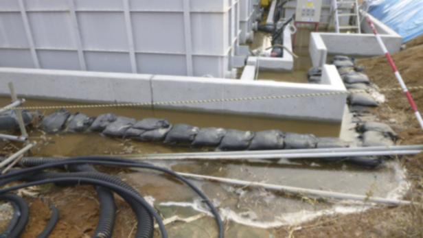 Schwarze Sandsäcke schützen ein Gebäude vor dem Hochwasser.
