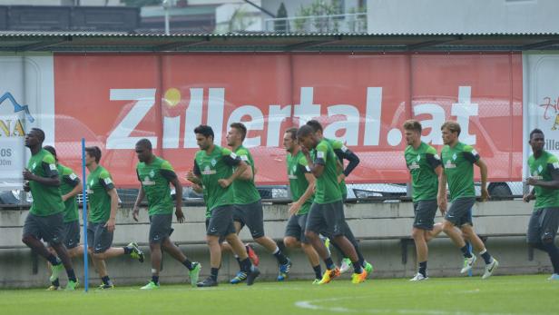 Eine Gruppe von Fußballspielern in grünen Trikots joggt auf einem Trainingsplatz.