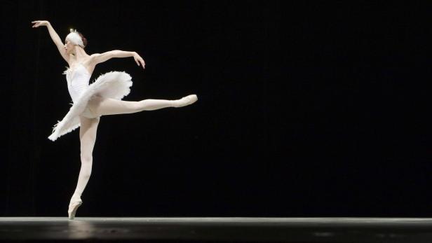 Eine Ballerina in einem weißen Tutu tanzt auf einer Bühne.