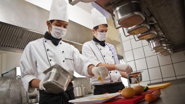 Chef and trainee work in a hotel kitchen, preparing a meal