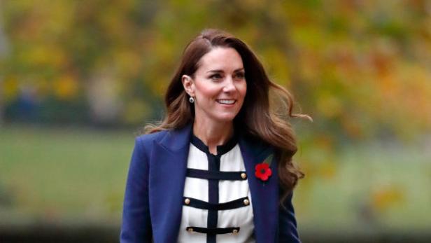 Kate Middleton in einem blauen Mantel und mit einer Mohnblume geschmückt.