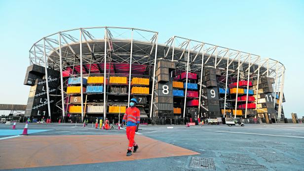 A worker walks in front of Ras Abu Aboud Stadium, one of the venues of the Qatar World Cup 2022, in Doha