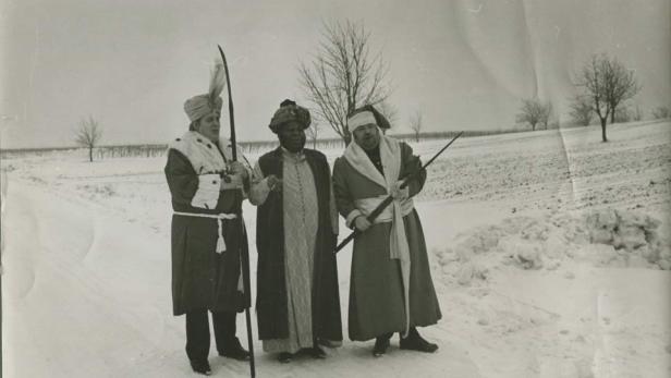 Drei als Könige verkleidete Männer stehen im Schnee.